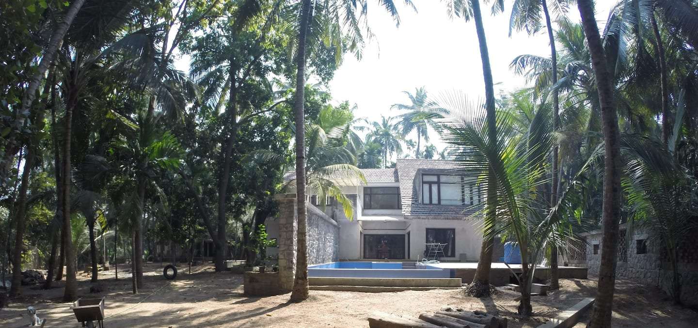 Outside view of the villa surrounded by tall palm trees and lush greenery