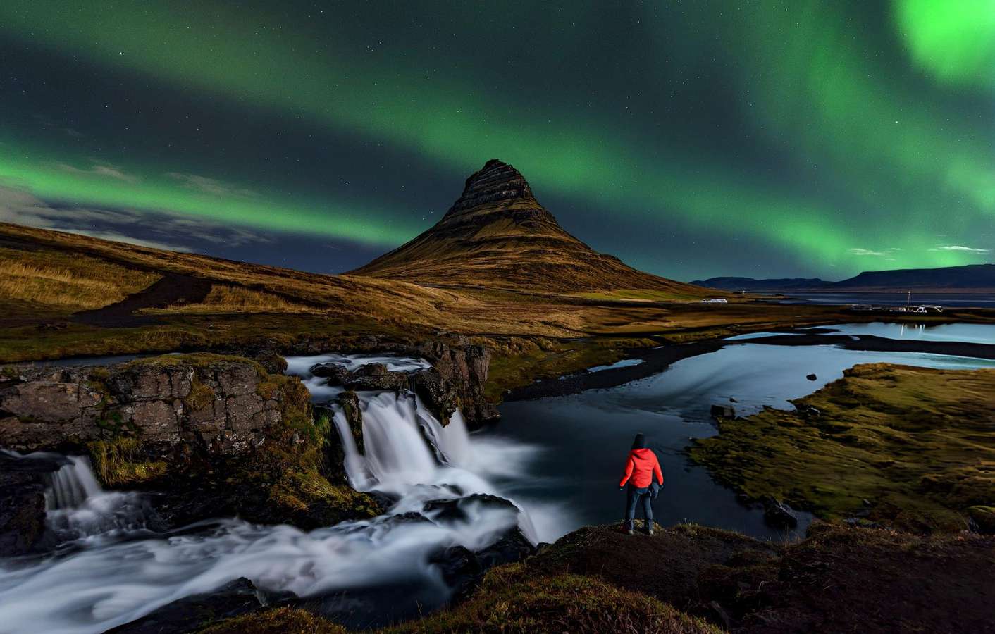 Tourist enjoying the view of Northern lights at Kirkjufell, Iceland