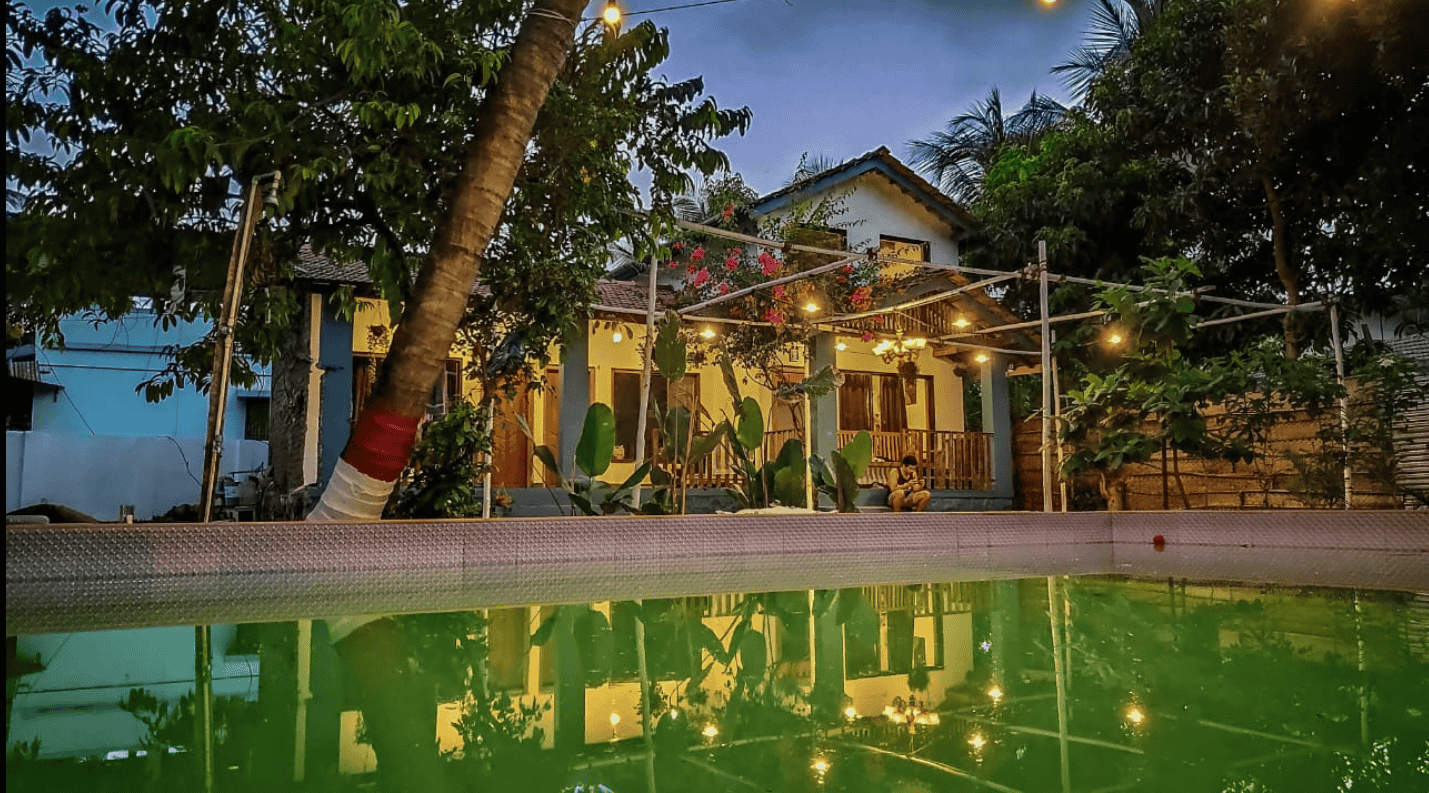 Outdoor view of the homestay with swimming pool and tropical trees 