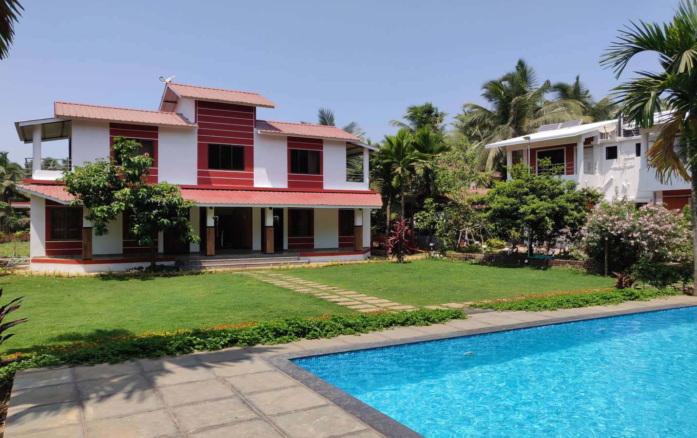Outdoors of the homestay sprawled with a lush green lawn and a well maintained swimming pool