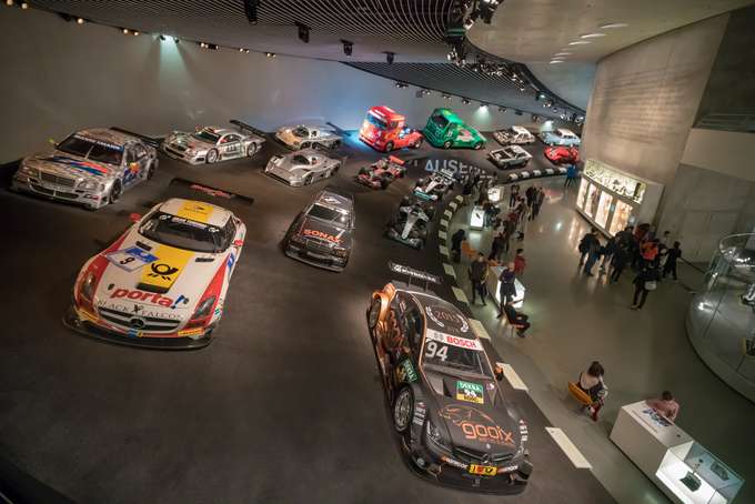 Stand among legendary Mercedes-Benz race cars and trucks in a dramatic motorsport display at Mercedes-Benz Museum